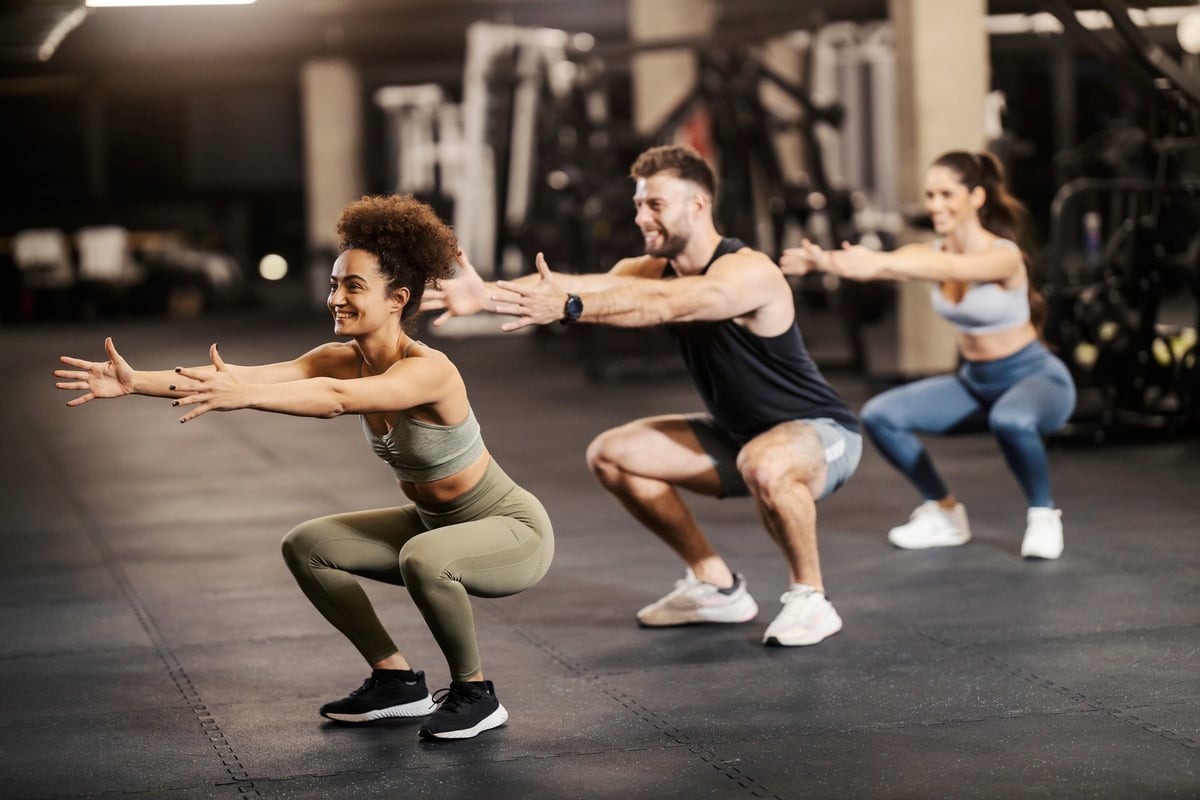 Two training partners pushing through a set of squats together in a BOOTFIT online session